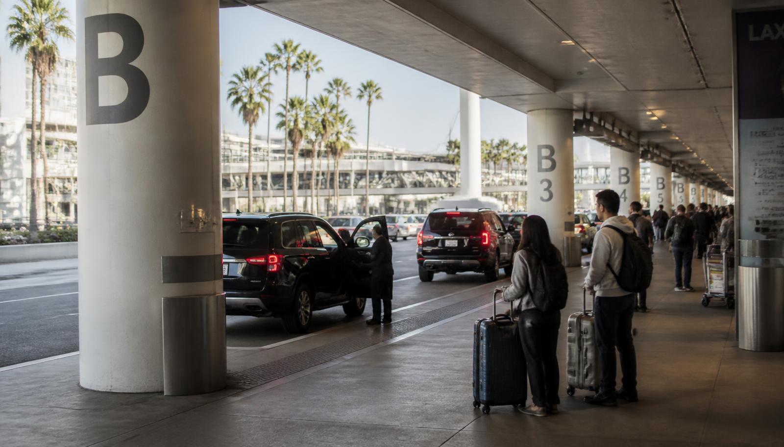LAX arrivals level curbside pickup area with lettered and numbered support columns and waiting passengers